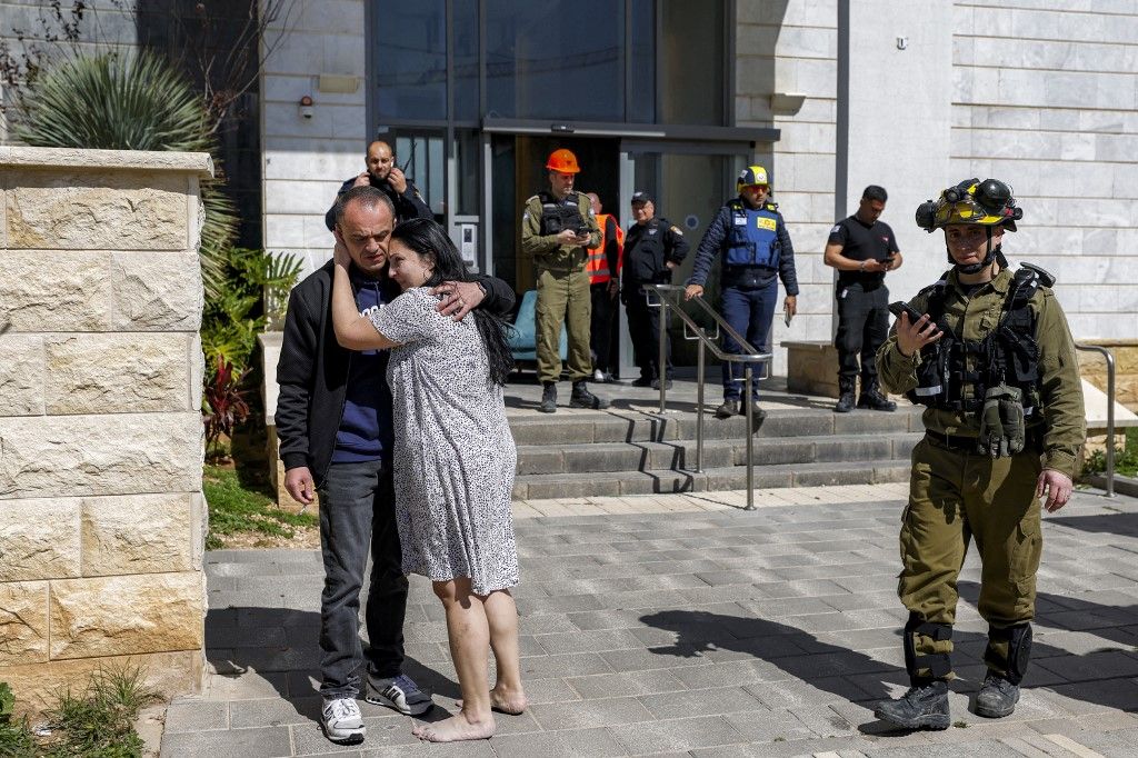 A man and woman embrace as residents of a building hit by a projectile are evacuated from the premises in Israel's northern city of Tirat Carmel, south of Haifa, on February 28, 2026. The United States and Israel launched strikes against Iran on February