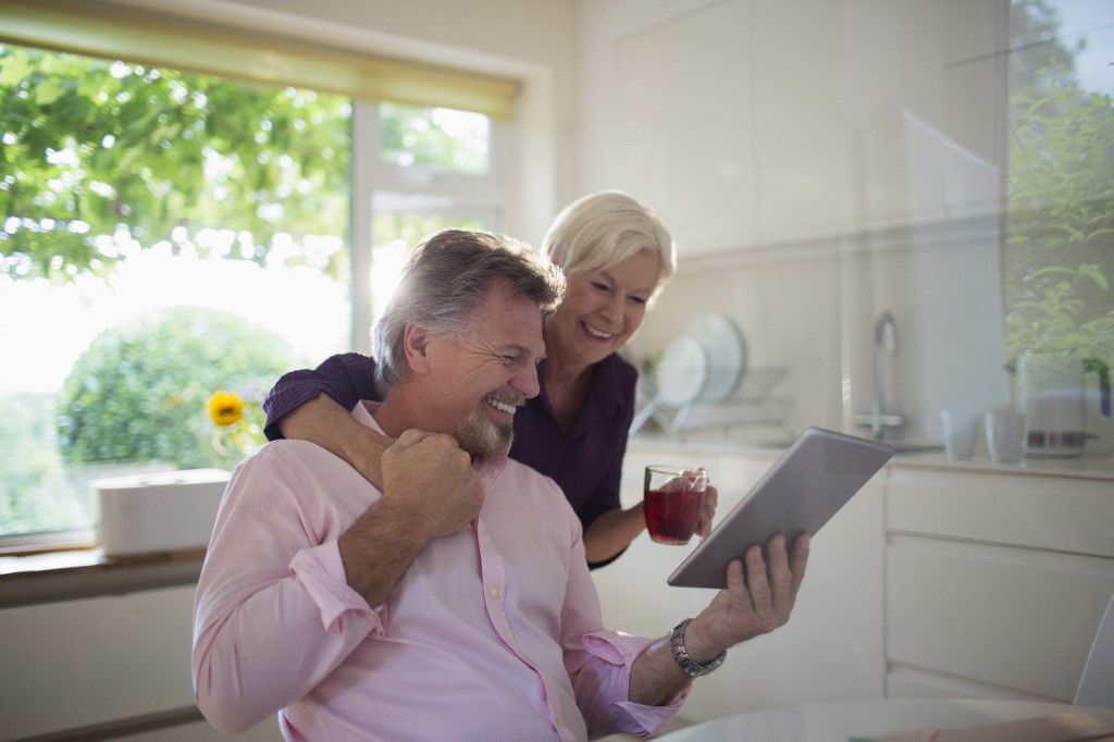 Happy senior couple using tablet in kitchen