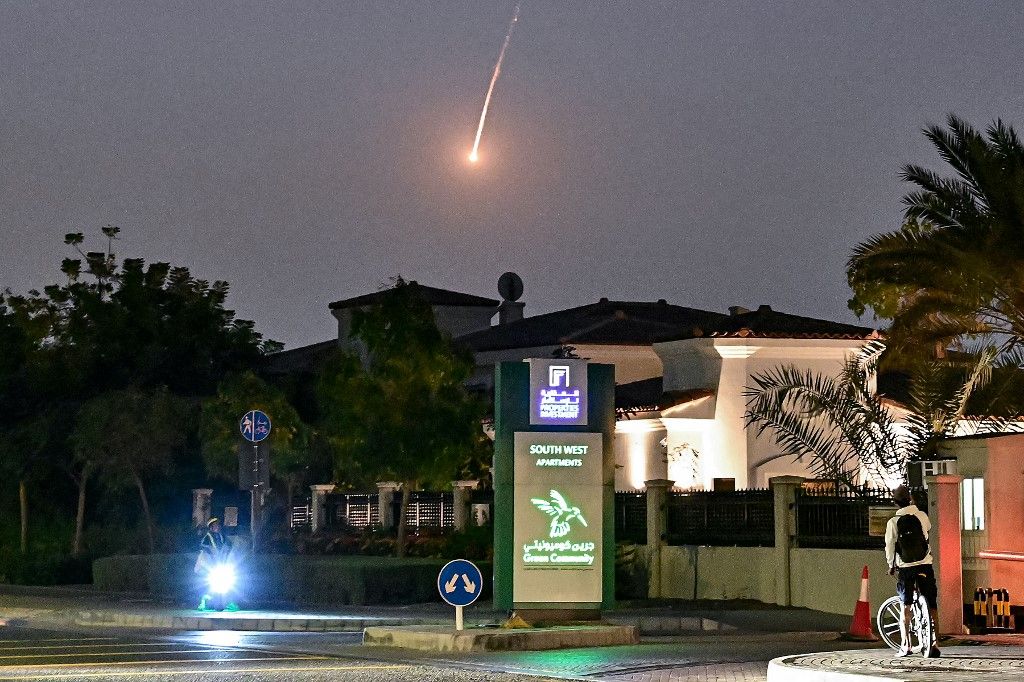 A cyclist watches as a projectile falls over Dubai on February 28, 2026. AFP correspondents heard a loud explosion in Dubai on February 28 and one of them saw a plume of smoke rising from the city. The explosions came in the wake of wide-ranging Iranian a