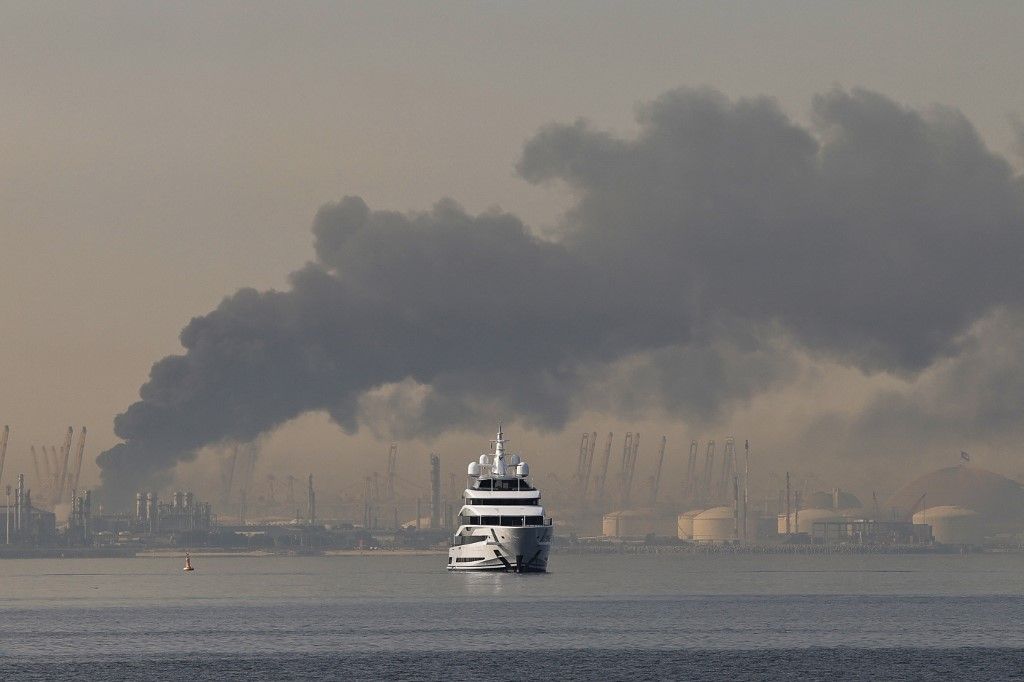 A yacht sails past a plume of smoke rising from the port of Jebel Ali following a reported Iranian strike in Dubai on March 1, 2026. Fresh blasts were heard across the Gulf cities of Dubai, Doha and Manama on Sunday morning after a day of Iran strikes in