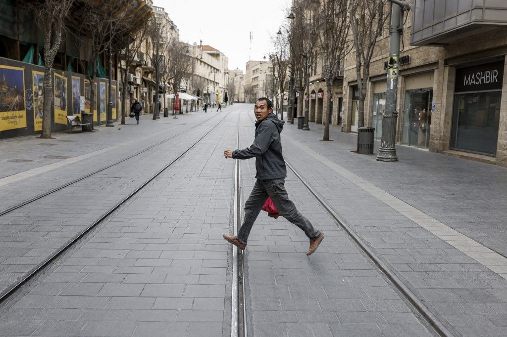A man runs across a street as sirens sound in Jerusalem on February 28, 2026. The Israeli military said its strikes on Iran, in coordination with the United States, targeted dozens of military sites and followed months of joint planning between the allies