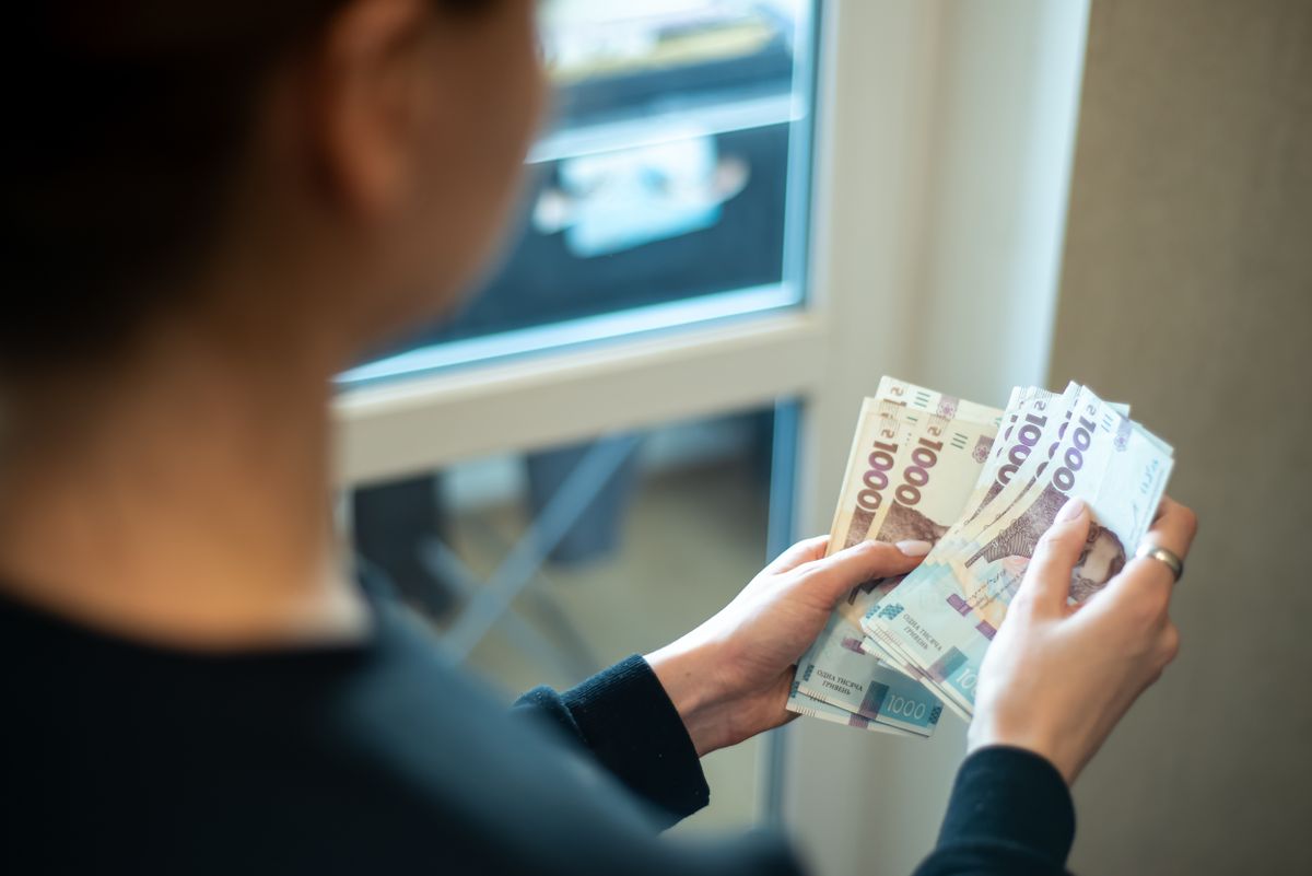 Women,Holds,Various,Banknotes,While,Standing,In,A,Bright,Room ukrán hrivnya ukrajna bér