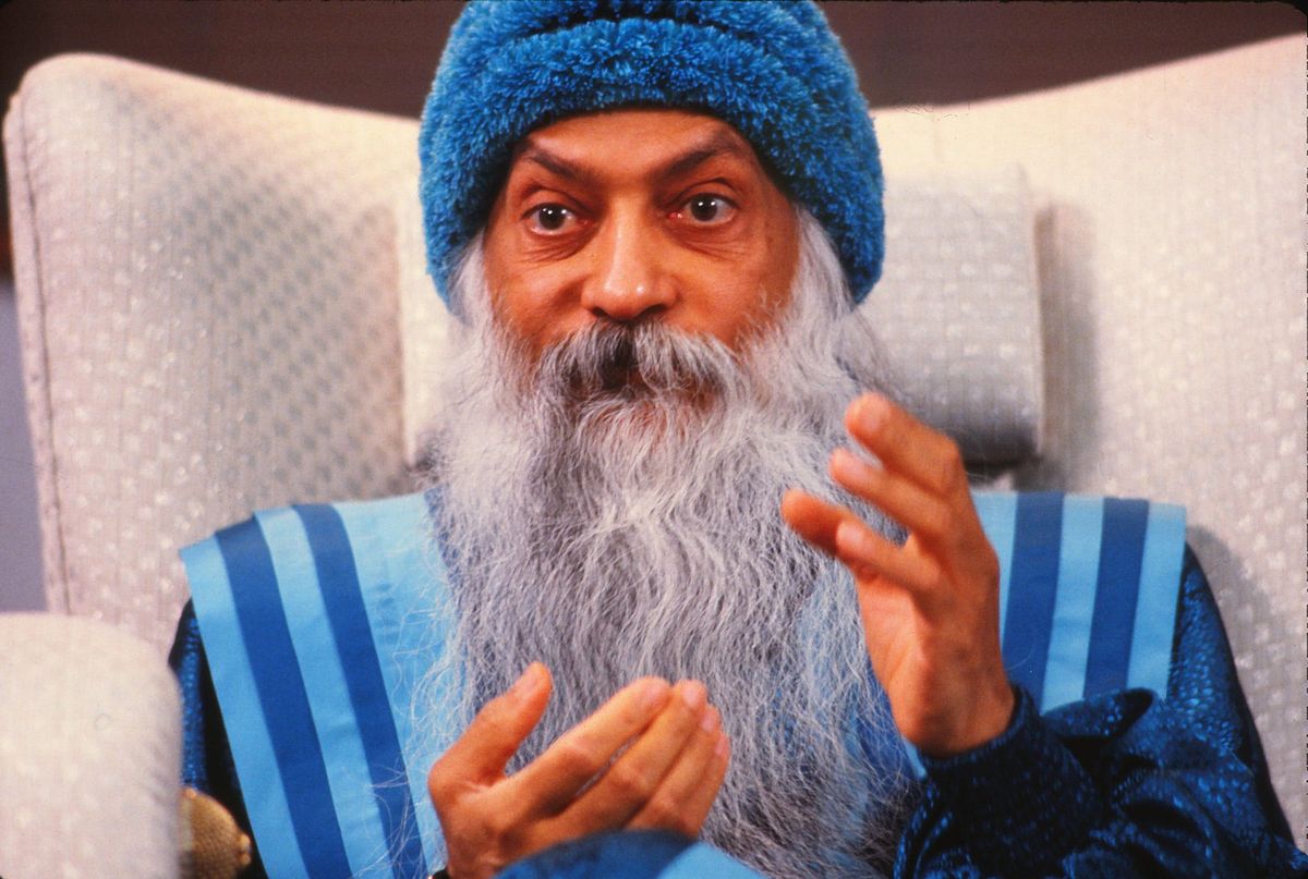 The doe-eyed spiritual leader Bhagwan Shree Rajneesh breaks his vow of silence to speak with media in the months before the