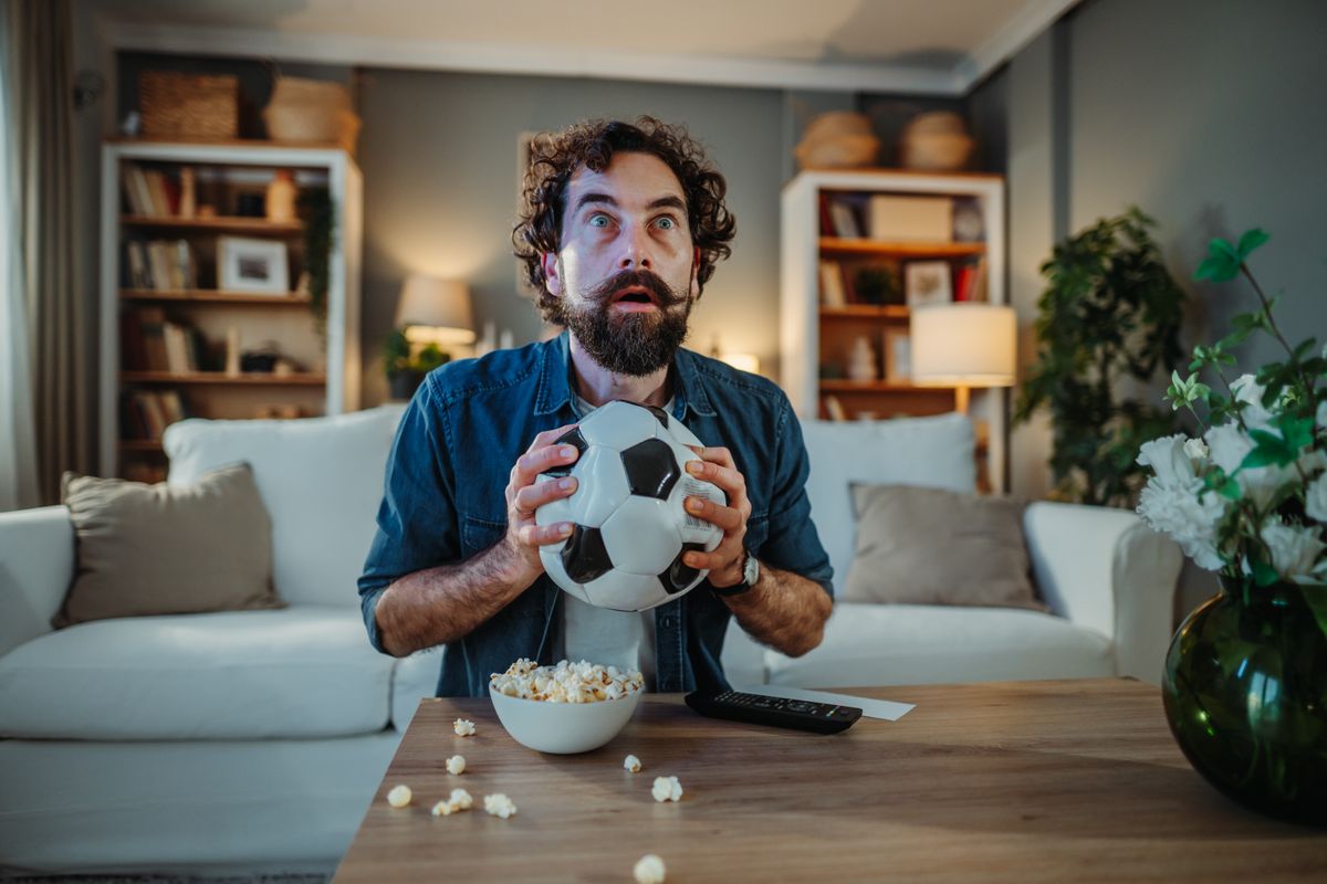 Stressed,Man,Holding,A,Soccer,Ball,,Watching,A,Thrilling,Game