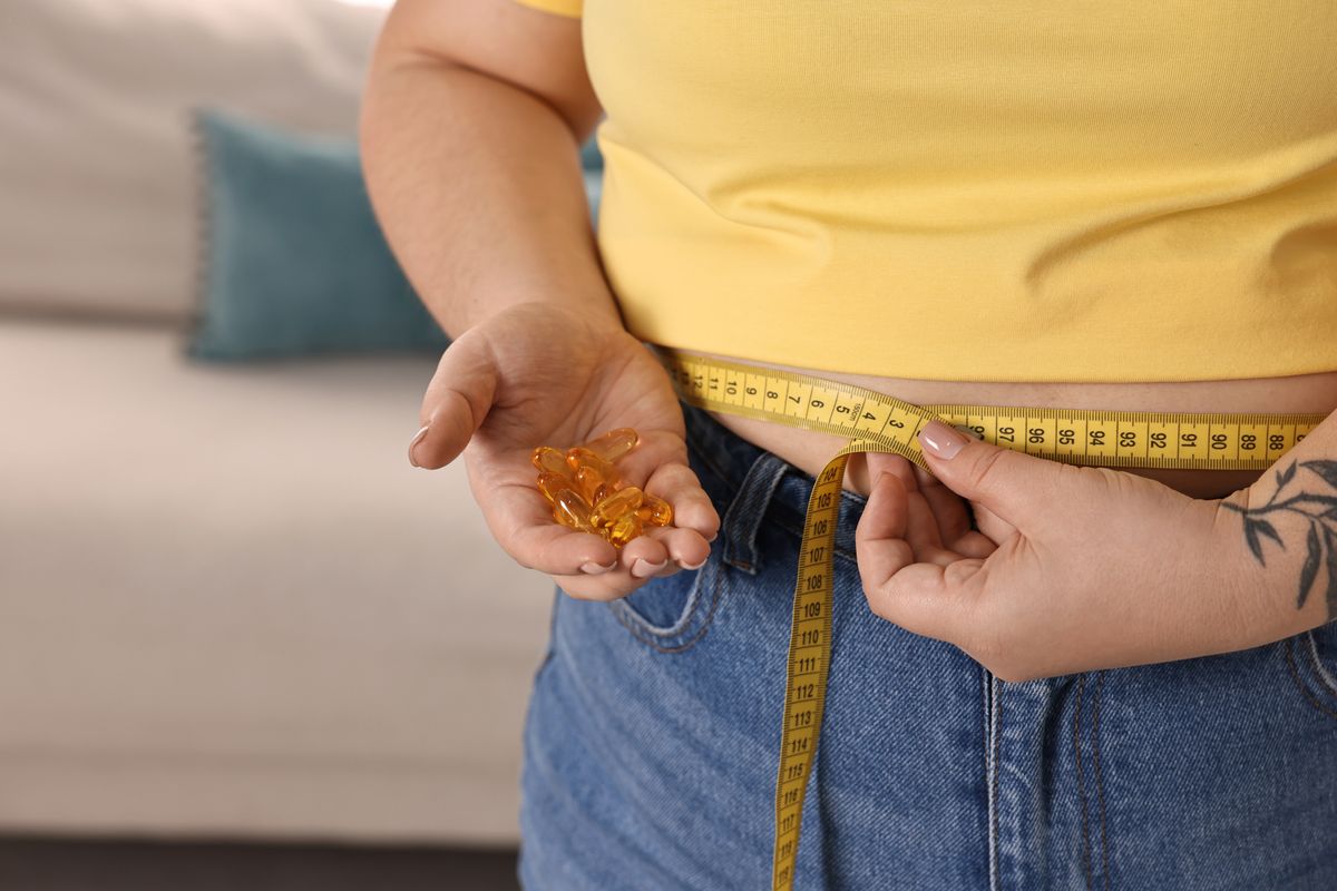 Plus,Size,Woman,Measuring,Waist,With,Tape,And,Holding,Pile