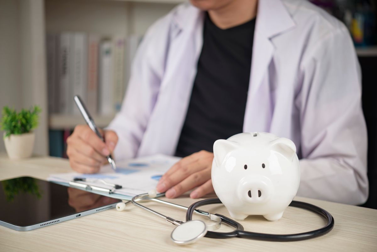 Doctor,With,Stethoscope,And,White,Piggy,Bank,On,Desk,,Concepts orvos fizetés egészségügy